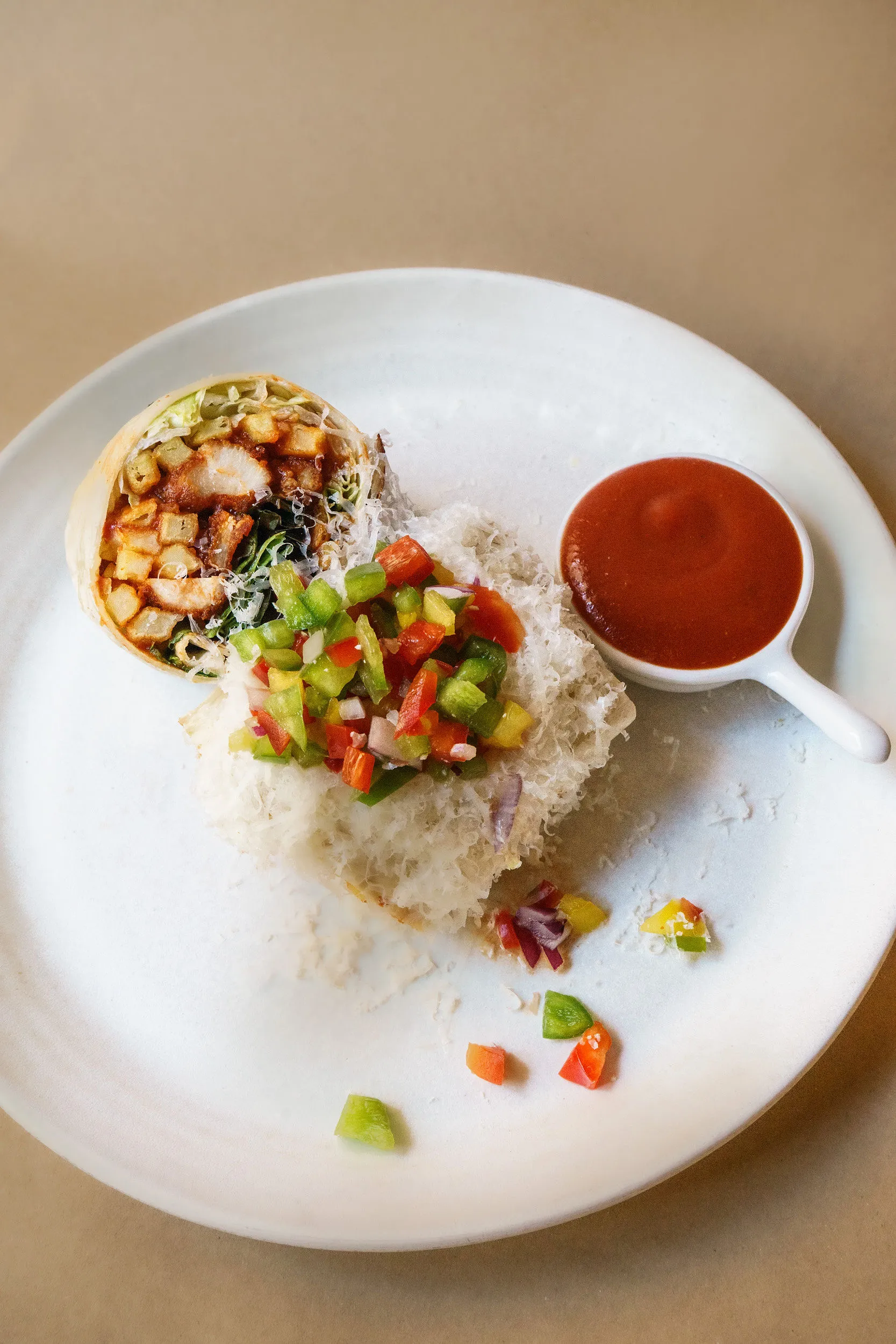 Chicken burrito cut open, with salsa salad and hot sauce