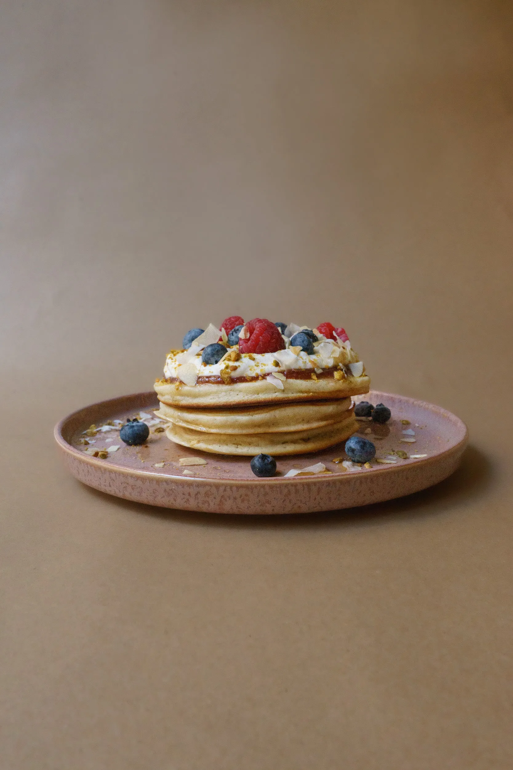 A stack of pancakes with berries and cream